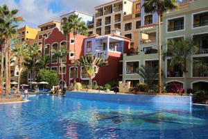 阿德耶Bahia Principe Sunlight Tenerife - All Inclusive的棕榈树和建筑度假村内的游泳池