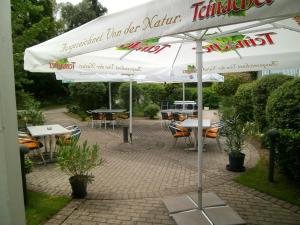 埃根斯泰因-列奥波德港尤尔根·法斯宾德运动酒店的庭院配有桌子、遮阳伞和桌椅