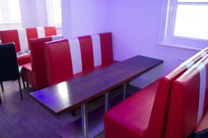 布莱顿霍夫Brighton Beach Inn的一间带木桌和红色椅子的用餐室