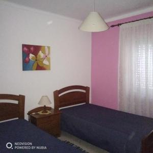 维拉·雷阿尔·德·桑托亚Apartamento Central的配有粉红色和紫色墙壁的客房内的两张床