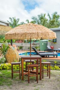 穆里Cook Islands Holiday Villas - Turangi Lagoon的草伞下的野餐桌和椅子