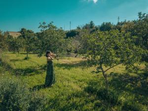 诺托Relais Terre di Romanello的站在田野的绿色连衣裙中的女人