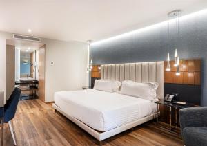 提华纳德尔里约真实酒店的卧室配有一张白色大床和一张书桌