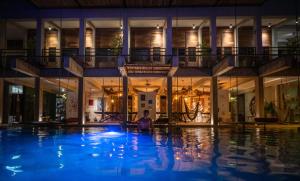 巴卡拉尔Hotel Makaabá Eco-Boutique的夜间坐在游泳池里的人