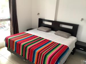 普拉亚卡门Condo Kiaraluna的床上有条纹的彩色毯子