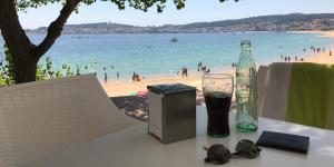 里贝拉Apartamentos Camping Coroso的海滩上一张桌子,上面放着一瓶和眼镜
