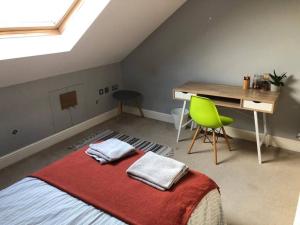 伦敦Twickes Townhouse的一间卧室配有一张带书桌和绿椅的床