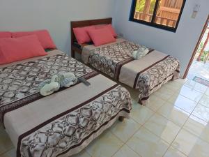 爱妮岛Hadefe Resort的客房设有两张床,铺有瓷砖地板。