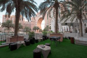 迪拜Oaks Ibn Battuta Gate Dubai的庭院里种有棕榈树,配有桌椅