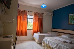 伊瓜苏Seibt Palace Hotel的客房设有两张床和一个带橙色窗帘的窗户。