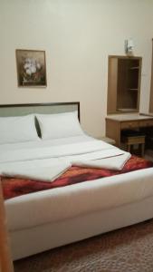 卢穆特Apartment Teluk Batik的一张带白色床单的床和一张桌子