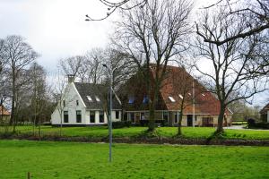 B&B Piebengastate Welsrijp的绿地中树木繁茂的白色房子