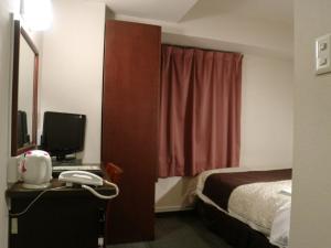 滨松Hamamatsu Station Hotel - Vacation STAY 65843的酒店客房配有一张床、一张书桌和一部电话
