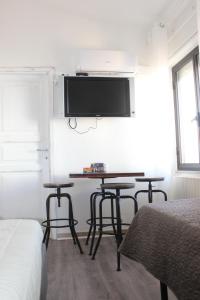 奥尔戈索洛B&B MARIMA 2 POSTI ORGOSOLO的一间设有两张桌子的房间和墙上的电视