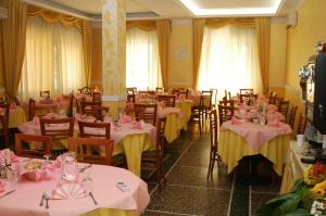 里米尼Hotel Giannella的配有桌椅、粉红色和黄色桌布的房间