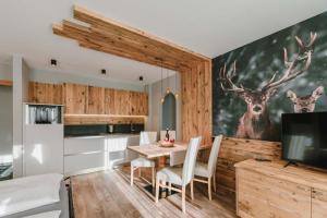 坎皮泰洛迪法萨Cesa Edelweiss Living & Spa的厨房配有餐桌和鹿画
