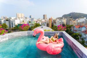 头顿La Casa Boutique Hotel的两个女孩坐在游泳池里一个充气的火烈鸟