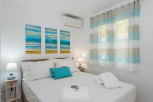 格利法达Waves Apartments Melody Glyfada的一间白色卧室,配有两张床和两个窗户