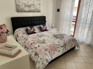 菲乌米奇诺AGM Suite Rome Airport FCO - Attico Parco Leonardo的一间卧室配有一张带花卉棉被的床