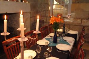 米塔贡菲茨罗伊历史之地米塔贡住宿加早餐旅馆的一张桌子,上面放着蜡烛、盘子和鲜花