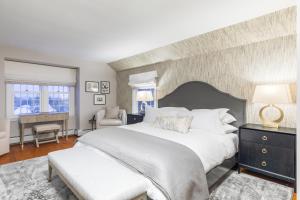 西多佛The Hermitage Inn Vermont的卧室配有一张白色大床和一把椅子