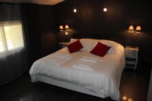 圣佩赖心藤旅馆的一间卧室配有带白色床单和红色枕头的床。
