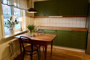 瓦斯泰纳Vadstena innerstad的厨房配有绿色橱柜和木桌及椅子