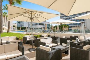 阿尔库迪亚港Trendhotel Alcudia - Adults Only的一个带椅子和遮阳伞的庭院和一个游泳池