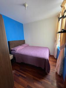 特鲁希略Exclusivo Apartamento en el corazón de Trujillo的一间卧室配有一张带紫色床单和蓝色墙壁的床。