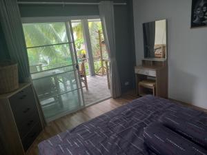 西塔努sweet home phangan的一间卧室设有一张床,并有通往阳台的门