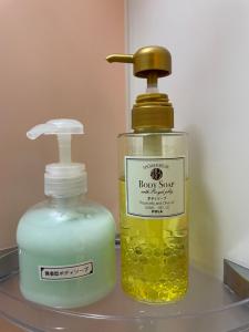 东京HotelHarmony日暮里ホテルハーモニー的架子上的一瓶肥皂和肥皂分配器