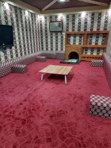 Madain Salehمزرعة ارياف العلا的一间设有桌子和电视的客房,铺有红地毯