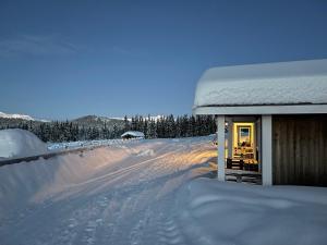 SkammesteinHytte på Myhre Gård的一条雪覆盖着的房屋,位于道路旁