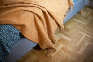 考纳斯Art & Comfort Home的木地板上床上的橙色毯子