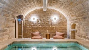 巴黎Le Petit Beaumarchais Hotel & Spa的石头建筑中的游泳池,配有两把椅子和一张桌子