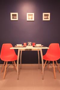 什切青Studencki Dom Marynarza Pasat的餐桌,带两把红色椅子和桌子及杯子