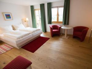 Wildsteig凯博格兰德酒店及客栈的一间卧室配有白色的床和两张红色椅子