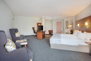 慕尼黑Holiday Inn Munich - South, an IHG Hotel的酒店客房带一张大床和椅子