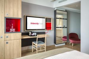 威斯巴登IntercityHotel Wiesbaden的配有书桌和电视的酒店客房