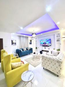 阿布贾Morak Homes - Luxury 4 bed home with PS5, 24hrs electricity, Super fast Wifi, Snooker, Games room - in a secured estate的客厅配有黄色和白色家具和电视