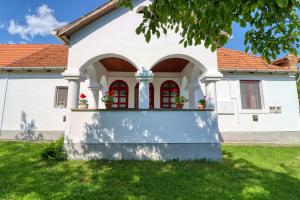 比克克塞克Napfény Vendégház的白色的房屋,设有红色的窗户