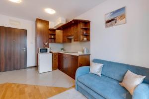 格但斯克Apartament Primavera的一间带蓝色沙发的客厅和一间厨房