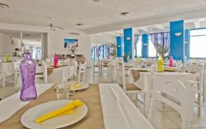 卡尔帕索斯Bluu Bahari Hotel的一间设有白色桌子和紫色花瓶的用餐室