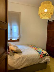 蓬费拉达Alojamiento estilo Boho con mucho encanto的一间卧室设有一张床、一个窗户和一个吊灯。