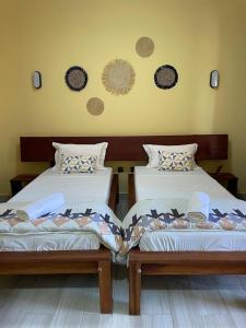 穆龙达瓦Havana Hôtel的两张睡床彼此相邻,位于一个房间里