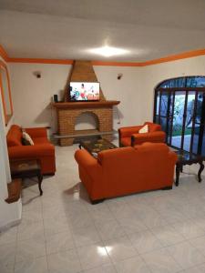 库埃纳瓦卡HERMOSA CASA EN CUERNAVACA: JARDÍN DEL LAGO的客厅配有橙色家具和壁炉