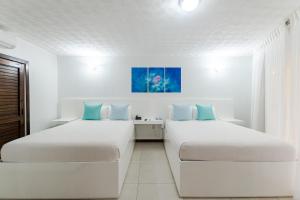 西湾天堂海滩酒店的配有白色墙壁和蓝色枕头的客房内的两张床