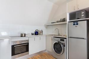 开普敦Urban Oasis Aparthotel的厨房配有白色橱柜、洗衣机和烘干机