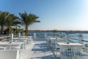赫尔格达Sunrise Tucana Resort Grand Select-的水边木板路上的一排桌椅