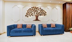 博帕尔Hotel Yuvraj Palace的墙上有一棵树的房间,有两张蓝色的沙发
